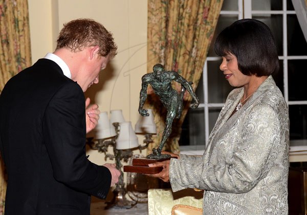 JIS
Prince Harry
His Royal Highness, Prince Henry of Wales (always known as Prince Harry), admires artwork depicting Jamaica’s athletic prowess, which was presented to him by Prime Minister, Most Hon. Portia Simpson Miller, just before the start of the State Dinner held in his honour last night (March 6) at King’s House.