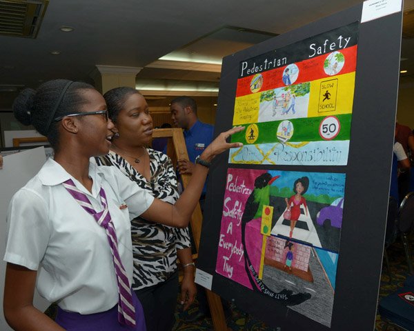 Ian Allen/Staff Photographer
Zhane' Gibson centre, student of Campion College, explains her entry in the National Road Safety Council(NRSC) road Safety Poster Competition to  her Mother Caleta Dunkley right. Ocassion was the NRSC Road Safety Poster Competition 2014 Awards Ceremony which was held at the Knutsford Court Hotel in Kingston on Thursday.