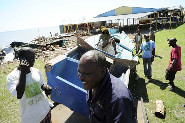 Ricardo Makyn/Staff Photographer
These men try to remove this Boat that was washed up on the Colonel Cove property  during the recent passage of Hurricane Sandy in Morant Bay