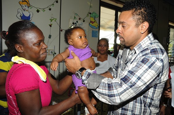 Ian Allen/Photographer
Shaggy right, takes 5 months old baby Kiomie Gentle from her mother Sycora Bent left, while on his annual christmas tour of the Bustamante Children Hospital where he gave gifts to some of the children.