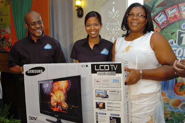 Rudolph Brown/Photographer
Pernal Elliston, Business Development Manager of Kraft Foods and Melissa Bennett, (second left) Brand Manager of Kraft Foods presents a TV to Clovel Folkes, Assistant Administrator of Dare to Care, Mustard Seed Foundation after she toss a Tang coin in the Fortune Fountain and win at the Tang Outreach press conference to launch the Tang Fortune Fountain at the Terra Nova Hotel in Kingston on Tuesday, August 28-2012