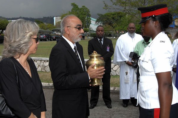 Ian Allen/Photographer
Charmaine Burrowes left, looks on as her brother Justice Andrew Rattray second left receive the Urn with the remains of his father Carl Rattray from a Woman Constable of Police just after the Official Thankgiving Service at the University Chapel, University of the West Indies Mona.