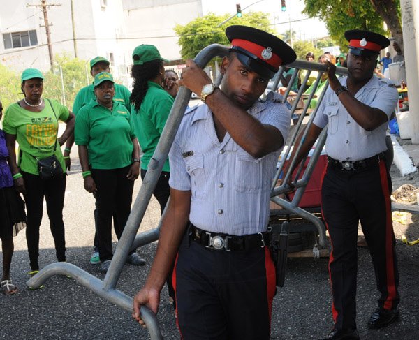 Jermaine Barnaby/Freelance Photographer
JLP supporters look as police carrying barricades to set up the state opening of Parliament at Gordon House on Thursday April 14, 2016.