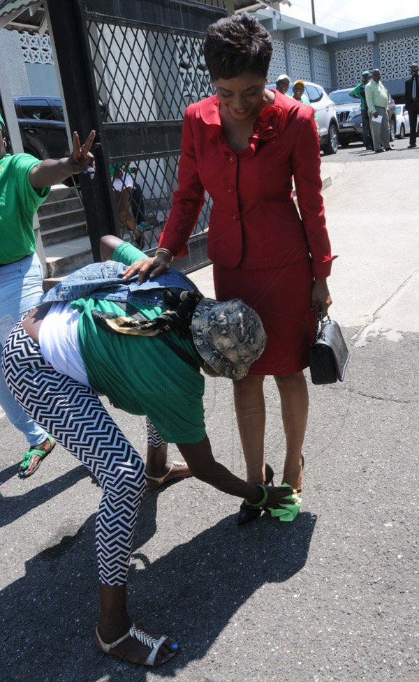 Jermaine Barnaby/Freelance Photographer
Debbie Burps cleaning the shoe of Marlene Malahoo Forte as she arrived for the state opening of Parliament at Gordon House on Thursday April 14, 2016.