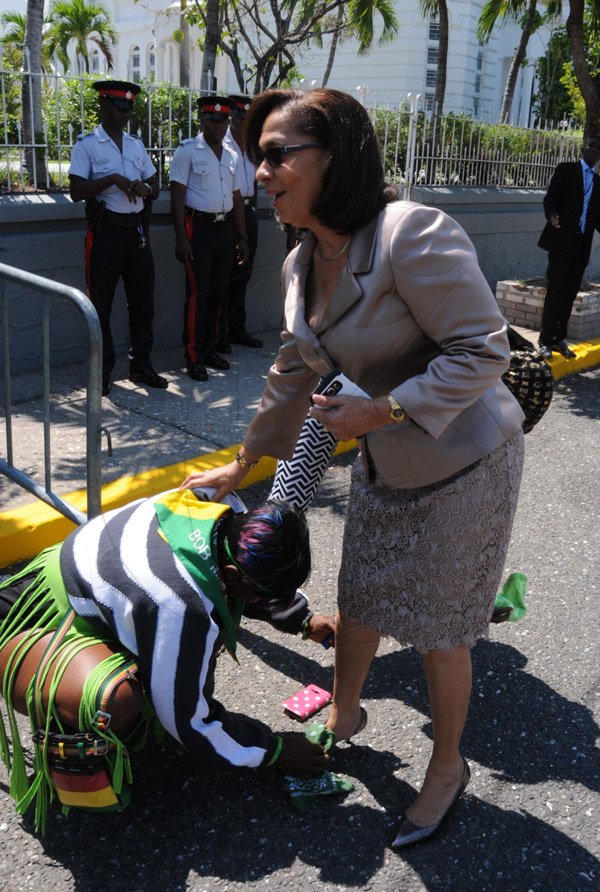 Jermaine Barnaby/Freelance Photographer
A supporter cleaning the shoe of Shahine Robinson as she arrived for the state opening of Parliament at Gordon House on Thursday April 14, 2016.