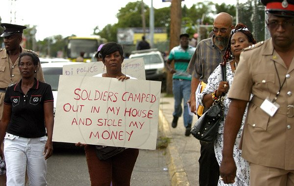 Gladstone Taylor / Photographer
Maxine Brown holds a placard accusing soldiers of unlawful behaviour during the incursion as walks to Jamaica House to present a signed petition requesting an international enquiry into the Tivoli incursion