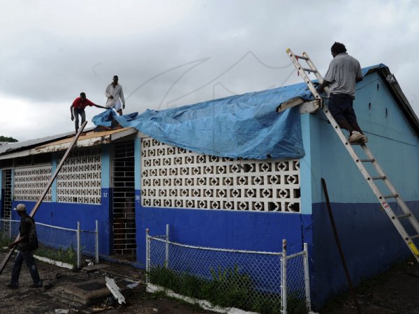 Norman Grindley/Chief Photographer
Workmen at the Swallowfield primary and Junior high school in St. Andrew cover a section of this class room that was blown off by hurricane Sandy.