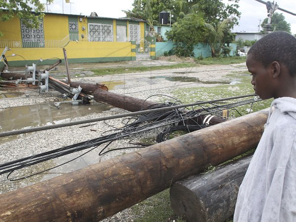Anthony Minott/Freelance Photographer
A boy watches a down utility pole in Braeton Phase one during the passage of Hurricane Sandy in Portmore, St Catherine last Thursday.