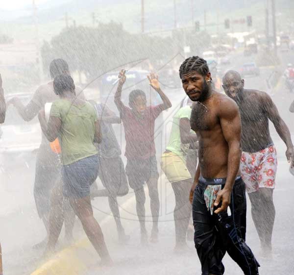 Rudolph Brown/Photographer
Residents of Riverton City take a bath after workmen laying cable on Spanish Town Road broken in main pipe wasting gallons water while NWC staff members on Strike on Tuesday, May 4-2010