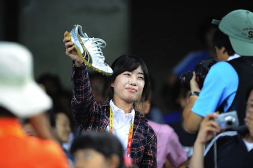 Ricardo Makyn/Staff Photographer                                   Fans got a hold of Bolt track shoes that was thrown in the crowd in Daegu.Sept.2,2011.
